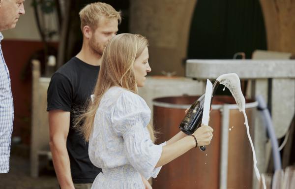 Bild 1 von 6: Das Sabrieren ist eine Kunst für sich. Normalerweise wird ein Säbel zum Köpfen der Sektflasche verwendet. Dorothea beweist zur Begrüßung eindrucksvoll, dass sie das auch mit dem Brotmesser schafft.