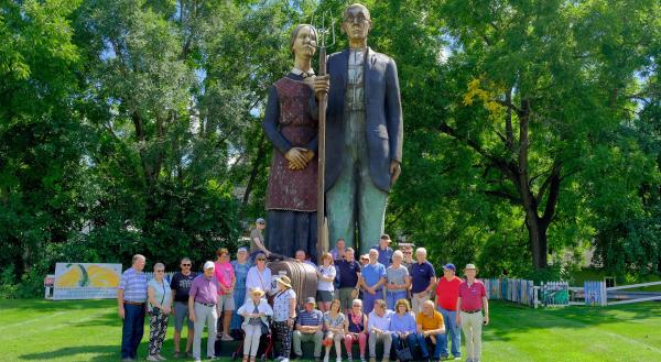 Bild 1 von 2: Die Reisegruppe in Anamosa Iowa vor einer Skulptur zur Erinnerung an den Ku?nstler Grant Wood.