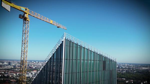 Bild 1 von 3: Ein Kran arbeitet am Estrel Tower, der mit rund 176 Metern Höhe zum höchsten Hotel Deutschlands anwachsen soll - ein Bau in luftiger Höhe, der Berlins Skyline dauerhaft prägen wird.