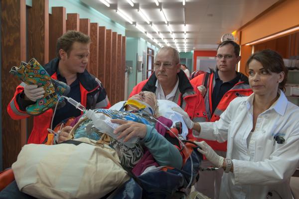 Bild 1 von 11: Notarzt Haase (Fabian Harloff, l.) und seine Rettungssanitäter (Komparsen) liefern die verunglückte Jette Kruse (Carmen-Maja Antoni, liegend) bei Jasmin (Gerit Kling, r.) im EKH ab.