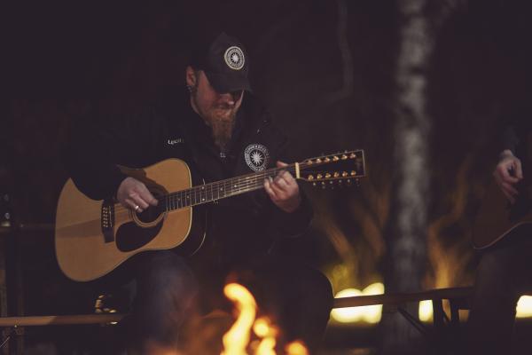 Bild 1 von 7: Lucki spielt Gitarre am Lagerfeuer.