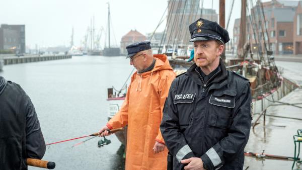 Bild 1 von 7: Timmermann (Mathias Junge, r.) treibt es zum Wismarer Hafen. Dort will er das Alibi von Hagen Franke, dem streitsüchtigen Nachbarn des Reiterhofs, überprüfen. Doch wie sich herausstellt, hat Hagen Franke gelogen. Er ist am Morgen nicht, wie behauptet, beim Angeln gewesen. Was hat er stattdessen gemacht? Hat er etwa das Drahtseil im Wald gespannt, um Gerald von Gungelitz umzubringen?