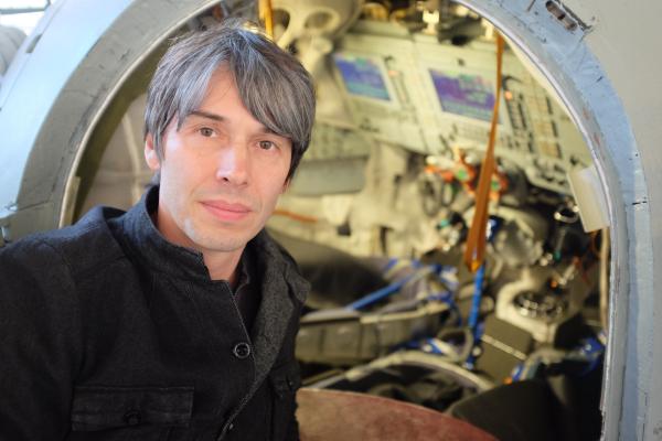 Bild 1 von 4: Presenter Brian Cox vor der Luke eines russischen Raumfahrzeugs im Sternenstädtchen bei Moskau.