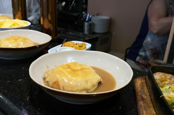 Bild 1 von 2: Die traditionsreiche Francesinha besteht aus Toastbrot, mehreren Fleischsorten sowie geschmolzenem Käse und wird mit brauner Soße serviert.