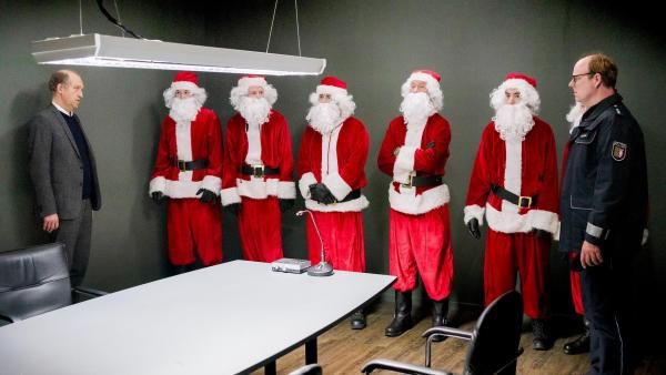 Bild 1 von 1: Im Bild: Carl Sievers (Peter Heinrich Brix, l.) und Polizist Schneider (Stephan A. Tölle, r.) mit fünf Weihnachtsmännern (Komparsen) bei einer Gegenüberstellung im Präsidium: Wer ist als Weihnachtsmann für den Raubüberfall verantwortlich, bei dem der Besitzer des Sylter Traditionshauses Betten Reuter erschossen wurde?