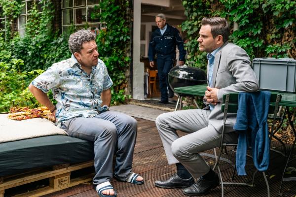 Bild 1 von 4: Kommissar Jonas Fischer (Lukas Piloty, r.) befragt den Tischler Janni Hauser (Jakob Schreier, l.) zu seiner toten Mitbewohnerin. (Komparse im Bild)