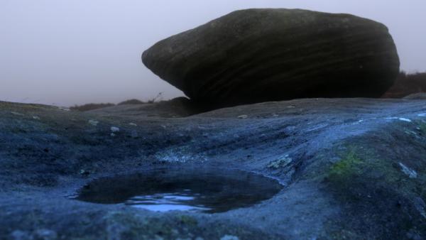 Bild 1 von 4: Carl Wark mit einem Fels und einer kraterartigen Vertiefung, die sich als Krater von Mörser-Übungen britischer Soldaten im Zweiten Weltkrieg erweist.