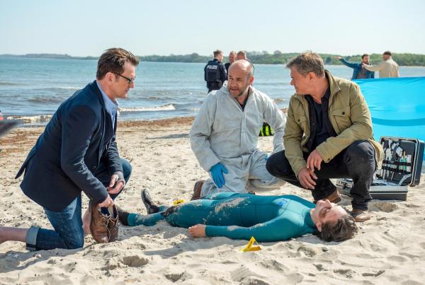 Bild 1 von 2: Im Bild: Eine unbekannte Frau wird tot aus dem Wasser geborgen. Lars (Ingo Naujoks, li.), Dr. Henning Strahl (Christoph Tomanek, mi.) und Finn (Sven Martinek, re.) begutachten die Leiche.