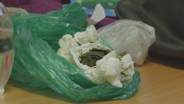 Bild 1 von 3: Zwischen den sichergestellten Gegenständen stößt das Zollteam auf eine in Papier gewickelte, grüne Masse - ein Fund, der weitere Untersuchungen nötig macht.