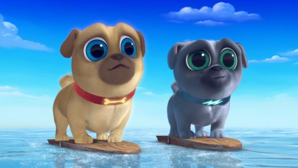 Bild 1 von 29: (a) Als Bob sagt, er würde gern Sand auf seinen Zehen spüren, unternehmen die Welpen eine Mission nach Hawaii. (b) Bob stellt den Welpen ARF vor, einen Roboterhund, der hinter ihnen aufräumt.