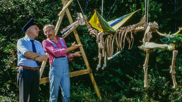 Bild 1 von 1: Peter (Peter Lustig, r.) hat einen riesigen Knochen im Garten gefunden. Ein so großer Knochen, denkt sich Peter, kann nur von einem großen Tier stammen - von einem Saurier! Er rekonstruiert das Skelett des Urwesens.
