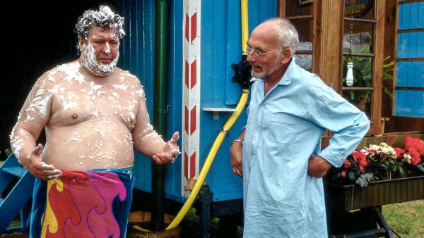 Bild 1 von 1: Komplett eingeseift taucht Nachbar Paschulke (Helmut Krauss, l.) in Peters Garten auf. Ihm wurde das Wasser abgeschaltet, jetzt muss er dringend bei Peter (Peter Lustig, r.) duschen.