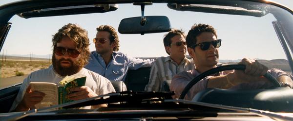 Bild 1 von 6: Zach Galifianakis as Alan reading book, seated in convertible with Ed Helms as Stu and Bradley Cooper as Phil in rear seat, and Justin Bartha as Doug in driver's seat.