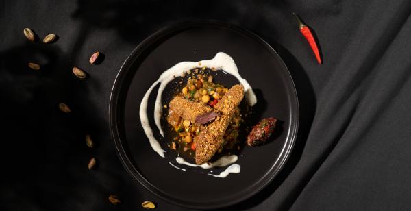 Bild 1 von 3: Klassischer tunesischer Salat aus gegrilltem Gemüse und dazu werden zarte Lammfilets mit Knusperpanade aus Pistazien serviert.