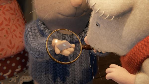 Bild 1 von 2: Sam (links) hat einen Schneestern auf einer kleinen Glasplatte eingefangen. Julia (rechts) staunt über das filigrane Muster des Schneesterns.