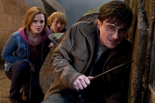 Bild 1 von 7: Daniel Radcliffe as Harrry Potter crouching and holding wand with Emma Watson as Hermione Granger, Rupert Grint as Ron Weasley