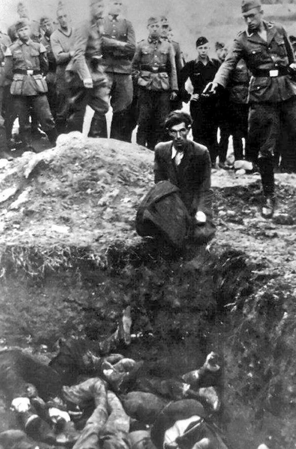 Bild 1 von 1: Juli 1941: Ein Nazi-Soldat posiert an einem Massengrab und ist im Begriff, einen Gefangenen zu erschießen. Im Oktober 2025 konnte die Identität dieses Mörders mittels KI aufgedeckt werden.