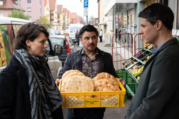Bild 1 von 4: Ein junger Paketzusteller wird erschlagen in seinem Lieferwagen aufgefunden und das SOKO-Team versucht seine letzte Route zu rekonstruieren. Die führt Nele Becker (Nina Siewert, l.) und Rico Sander (Benjamin Strecker, r.) zu Cem Sükür (Ercan Karaçayli, M.). Sein Laden fungiert als halboffizielle Zentrale aller Paketfahrer des Viertels. Kann er bei den Ermittlungen weiterhelfen?