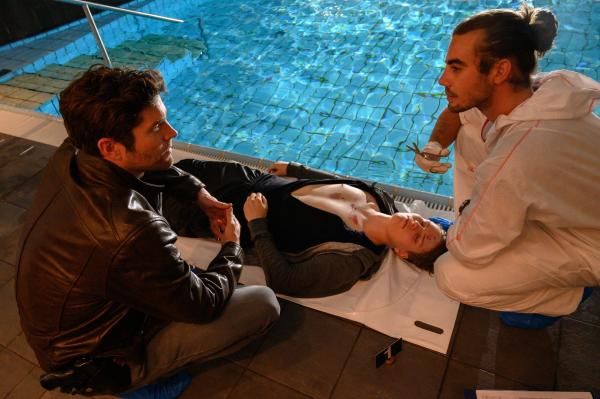 Bild 1 von 3: Paul Steinfeld (Stefan Siewert,M.) hat in einer Rehaklinik im Bundesfreiwilligendienst gearbeitet. Jetzt liegt er tot neben dem Pool der Klinik. Können erste Erkenntnisse von Benedikt Förster (Florian Wünsche, r.) über Opfer, Tatwaffe und gegebenenfalls Tathergang Jo Stoll (Peter Ketnath, l.) bereits den richtigen Weg weisen?