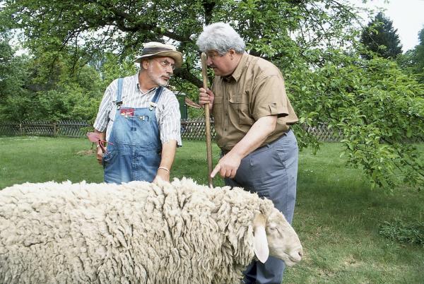 Bild 1 von 2: Nachbar Paschulke (Helmut Krauss, r.) zeigt Peter Lustig (Peter Lustig, l.) sein neues Schaf. Er fürchtet um dessen Leben, denn seit kurzem ist Wolfsgeheul zu hören.