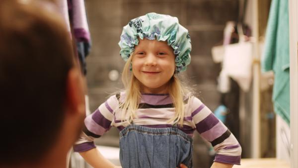 Bild 1 von 3: Vilda (Sofia Sittnikow) trägt vorsichtshalber eine Duschhaube, damit sie keinen ansteckt.