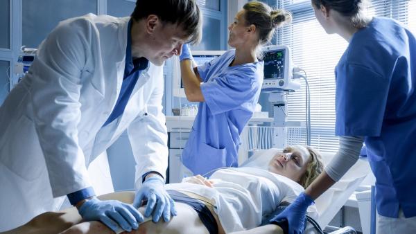 Bild 1 von 8: Im Bild: Dr. Ludwig (Sebastian Hülk) behandelt Blums (Anna Maria Mühe) Stichverletzung, während die Krankenschwester (Claudia Kainberger) ihr eine Infusion gibt.