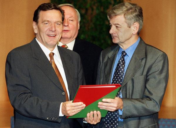 Bild 1 von 3: Der designierte Bundeskanzler Gerhard Schröder (l.) und der designierte Außenminister Joschka Fischer (r.)  von den Grünen präsentieren nach der Unterzeichnung am 20. Oktober 1998 den rot-grünen Koalitionsvertrag in der NRW-Landesvertretung in Bonn.