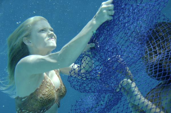 Bild 1 von 5: Cleo (Phoebe Tonkin, im Netz) hat sich bei ihrer Suche nach dem illegalen Schildkröten-Fischer in einem Fischernetz verfangen. Sie wird von Rikki (Cariba Heine, li.) befreit.
