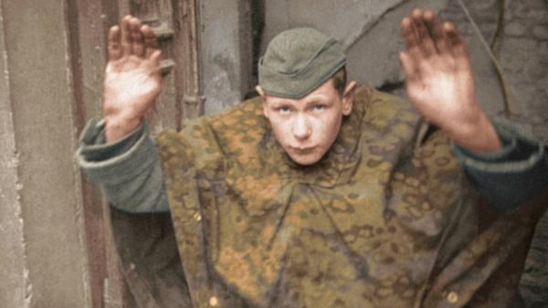 Bild 1 von 2: Ein Hitlerjunge ergibt sich vor russischen Truppen. Obgleich viele unter ihnen nicht einmal volljährig waren, wurden zahlreiche Kindersoldaten der 12. Panzerdivision als Kriegsverbrecher verurteilt.