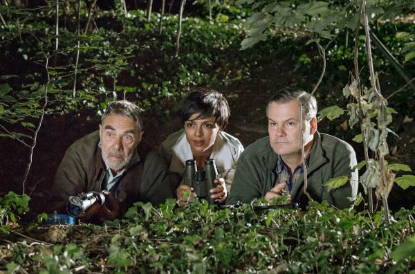 Bild 1 von 3: Hochkonzentriertes Warten auf den Wolf. Dieses aufregende nächtliche Schauspiel lässt sich Zoodirektorin Amal Bekele (Dennenesch Zoudé, Mitte) nicht entgehen. Professor Baumgart (Gunter Schoß, links) und sein Kollege vom BUND Hans Gründling (Tom Quaas, rechts) sind auf die Begegnung mit dem wilden Tier gut vorbereitet.