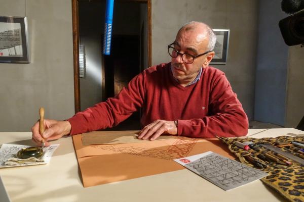Bild 1 von 3: Kalligraf Abd Masoud schreibt die Inschrift des Krönungsmantels nach.