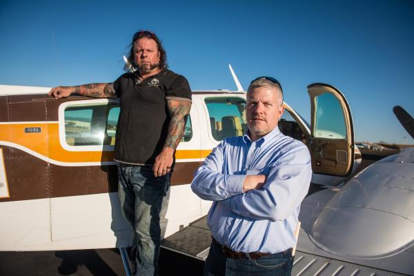 Bild 1 von 1: Ken Cage and Danny Thompson outside an airplane.