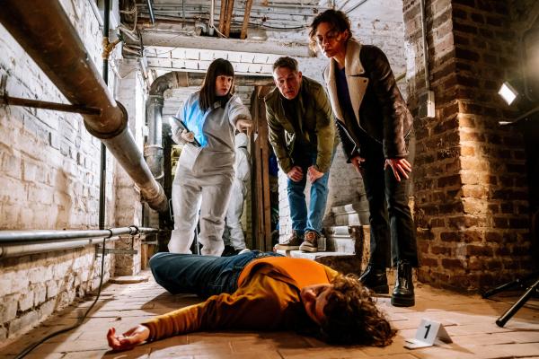 Bild 1 von 3: Valeria Greco (Sophie Killer, liegend) wird tot an der Kellertreppe ihrer Wohnung gefunden. Doch wie Dr. Westphal (Yulia Yáñez Schmidt, l.) den Kommissaren Matti Wagner (Pierre Besson, M.) und Lilly Funke (Tatjana Kästel, r.) berichtet, muss sie jemand mit böser Absicht ermordet haben, denn sie wurde vorher schon erstickt.
