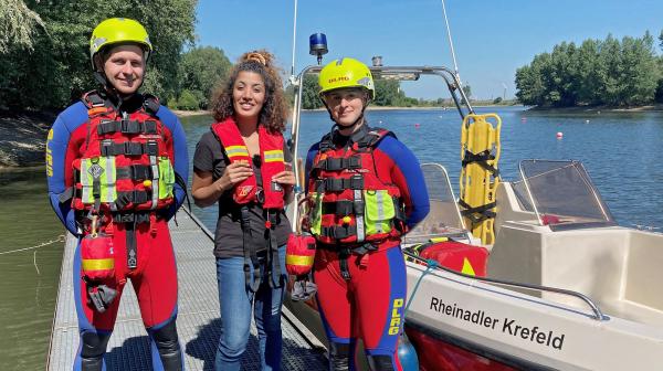 Bild 1 von 6: Reporterin Tessniem (Mitte) steht zwischen den DLRG-Strömungsrettern Kevin (links) und Cécile auf einem Steg. Wie gefährlich ist es, im Rhein zu baden?