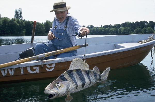 Bild 1 von 2: Peter (Peter Lustig) hat sich einen großen Fisch gebastelt. Im Inneren des Fisches steckt eine Kamera. Peter wird den Fisch schwimmen lassen, vielleicht erhält er so Fotos von dem Bärstädter See-Monster.