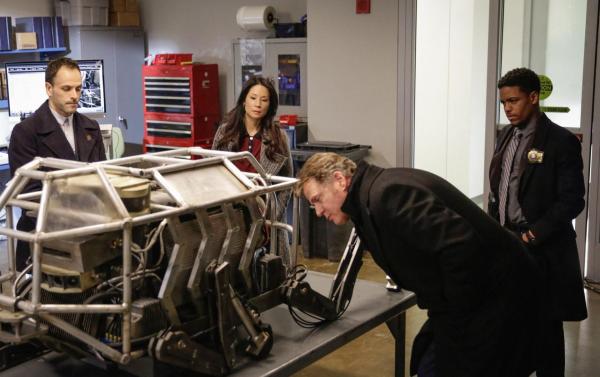 Bild 1 von 9: Als der Bruder von Henry Baskerville ums Leben kommt, werden Holmes (Jonny Lee Miller, l.) und Watson (Lucy Liu, M.) zu dem Fall hinzugezogen. Zusammen mit Captain Gregson (Aidan Quinn, vorne) und Detective Bell (Jon Michael Hill, r.) stoßen sie schnell auf Ungereimtheiten ...