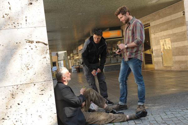 Bild 1 von 7: Jo Stoll (Peter Ketnath, r.) und Rico Sander (Benjamin Strecker, M.) befragen einen Obdachlosen (Komparse, l.). Er trägt die Schuhe und das Jackett des Opfers. Hat er auch etwas mit dessen Tod zu tun?