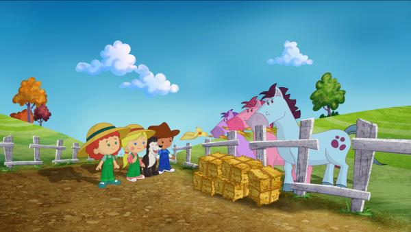 Bild 1 von 3: Tanja, Zoé, Hofhund Freddie und Finn füttern die Pferde mit Stroh.