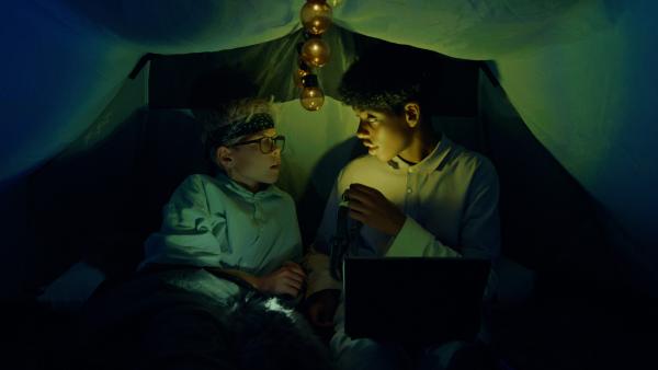 Bild 1 von 2: William (Caleb Kebreab, rechts) will Mattis (Leon Mosand-Christensen, linkls) überreden, einen Horrorfilm im Zelt zu schauen.