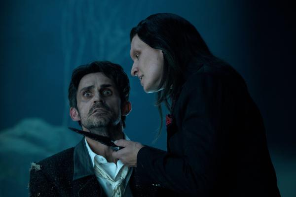 Bild 1 von 3: Calypso (Anthony Carrigan, r.) bestraft Mr. Grimm (Richard de Klerk, l.) für seinen Regelverstoß und entzieht ihm das, was ihm am wichtigsten ist.