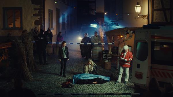 Bild 1 von 6: Karina Droste (Hilde Dalik) kniet vor ihrem ermordeten Mann Hubert Droste (André Rohde) draußen auf einer nächtlichen Straße.