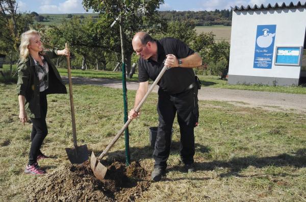 Bild 1 von 1: Moderatorin Anna Lena Dörr und Thomas Ripplinger vom Viezhof pflanzen im Lutherjahr ein Apfelbäumchen.