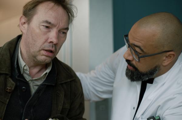 Bild 1 von 5: Dr. Evans (Tino Führer, r.) kümmert sich um Paul Dreyer (Thomas Arnold, l.), der offensichtlich auch bei dem Unfall in einem Straßencafé schwer verletzt wurde.