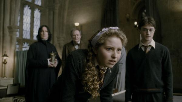Bild 1 von 15: Alan Rickman as Professor Severus Snape standing in room next to Jim Broadbent as Professor Horace Slughorn, Jessie Cave as Lavender Brown in foreground, and Daniel Radcliffe as Harry Potter standing aside.