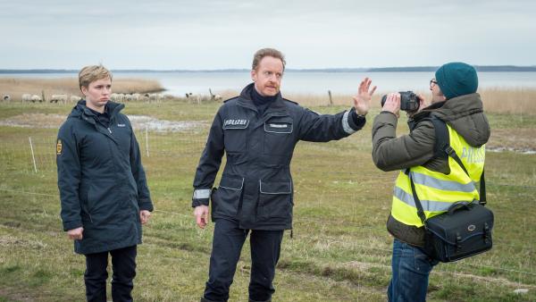 Bild 1 von 7: Auf der Schafsweide macht Reporter Richard Lister (Thilo Hermann, r.) ungefragt Fotos vom Tatort. Timmermann (Mathias Junge, M.) fordert ihn auf, dies sofort zu unterlassen. Austauschpolizistin Stine (Sidsel Hindhede, l.) unterstützt ihn dabei. Lister behauptet, gehört zu haben, ein Wolf habe den Schäfer getötet. Kein Kommentar! Was der Reporter zu diesem Zeitpunkt allerdings noch nicht weiß: Erste Indizien sprechen sehr wohl dafür, dass die SOKO es mit einem Mord zu tun hat.