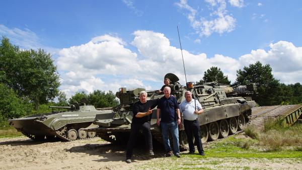 Bild 1 von 4: Nigel Dunkley, Lawrence G. Kelley und Jean-Paul Staub vor einem ehemaligen NVA-Bergepanzer, Drehpause in der ehemaligen Sowjet-Kaserne in Mahlwinkel.