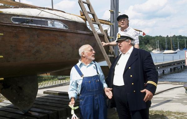 Bild 1 von 3: Irgendwie ist Herr Paschulke (Helmut Krauss, r.) doch stolz, nun der Besitzer eines Segelbootes zu sein. Es ist aber noch viel zu tun, bis es zu Wasser gelassen werden kann. (l. Peter Lustig)