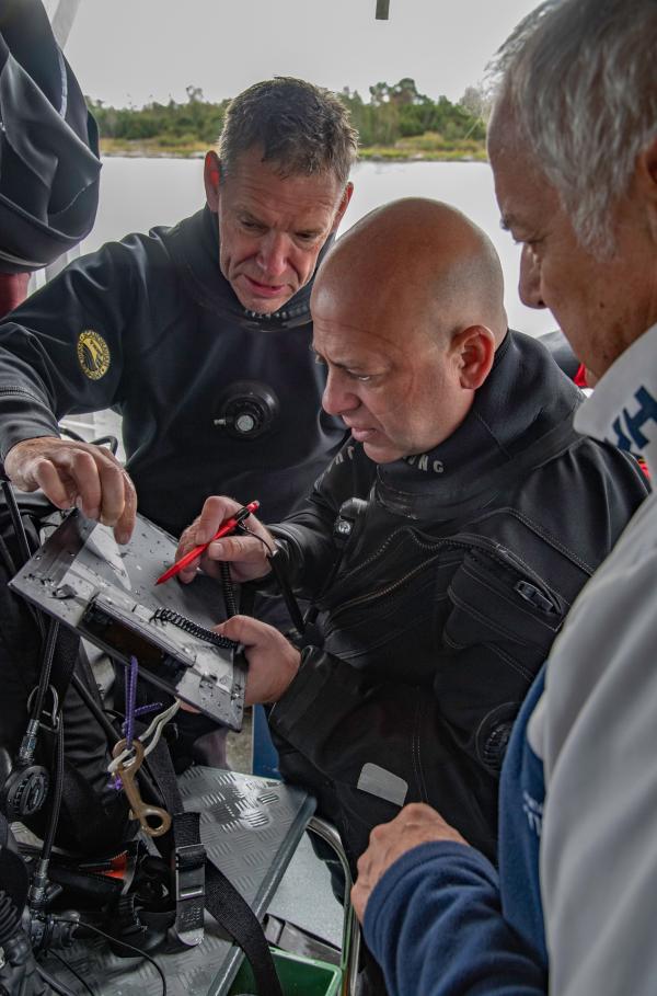 Bild 1 von 6: Die Taucher prüfen die Ausgrabungspläne an Land.