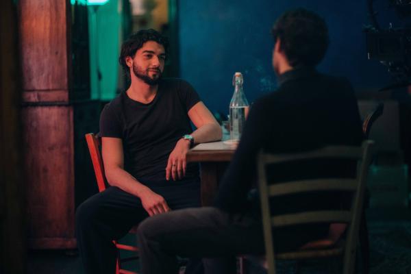 Bild 1 von 2: Lorenzo (Giacomo Giorgio, l.) sitzt in seiner Wohnung am Küchentisch und hat Besuch von einem Bekannten (Komparse).