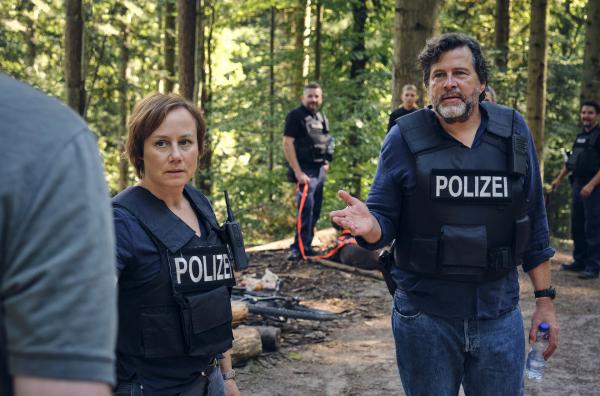 Bild 1 von 2: Die Kommissare Franziska Tobler (Eva Löbau) und Friedemann Berg (Hans-Jochen Wagner) müssen im Wald ein geflüchtetes Paar aufspüren.